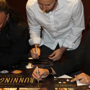 Jon Proudstar Brent Ryan Green and Booboo Stewart autographing a poster following the premiere of Running Deer