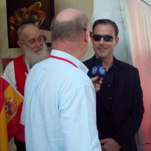 Daniel Wilson is interviewed by a local television reporters at the world premiere of The Long Weekend in Marbella Spain while actor Frank Taylor looks on