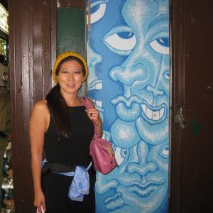 Lil Rhee standing in front of a door painted by artist Andy Golub