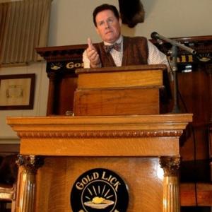 Ben McCain as the Mayor of Gold Lick, addressing the citizens.