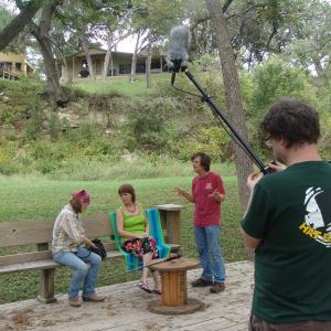 Melinda Ellisor, Gina McClure and Rodger Marion discuss a scene. Morgan Marion adjusts the microphone.