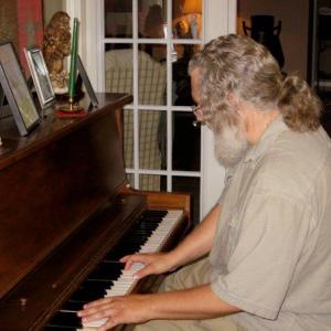 Mark Connelly Wilson plays upright piano  writing music for Land of Leopold
