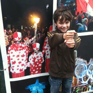 Valin in front of photo of himself carrying the games torch in the Whistler city square