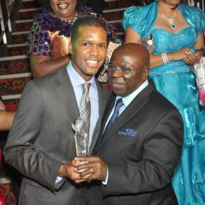Altorro Prince Black poses for photo with the Ambassador after he receives his Best Supporting Male award in Missing Link given by Phinchic Movies from The Honourable Ambassador of Nigeria to Canada His Excellency Prof Hagher