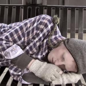 A hobo Brandon Burns sleeps on a park bench near the train station