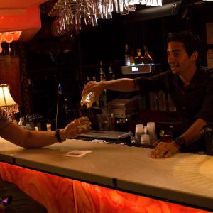 Monchi the bartender serves a drink to Alejandro Cuevas in the Telemundo TV series Incgnita