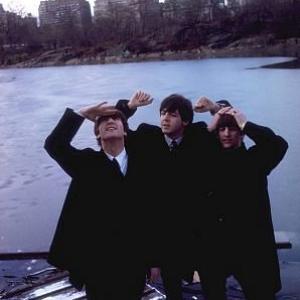 The Beatles (John Lennon, Paul McCartney, Ringo Starr in their overcoats with the city in the background),