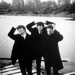 The Beatles John Lennon Paul McCartney Ringo Starr with hands on their heads City in the background