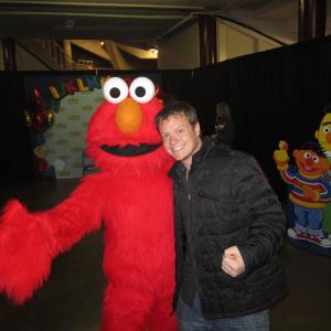 29 Frame Productions Kevin Wilson standing with Seasame Streets Elmo