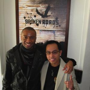 Rey and writer/director Justin Chambers in front of Broken Roads poster