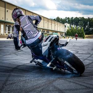 Stuntwoman Crystal Hooks sitting in the highchair position drifting her freestyle motorcycle