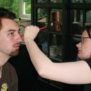 Behind the scenes special effects makeup artist Anita Ashbaugh applies signs of alcoholism to Llian Breen in preparation for the scene Larry Beats Regardless from The Messenger by Kade Mendelowitz