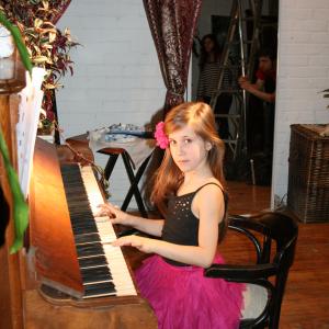 Gloria posing with the piano on the set of ABOUT THE AUTHOR