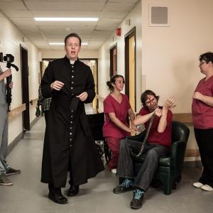 Ryan center in costume as Father Bane directs his crew and background actors on the set of Holy Hell