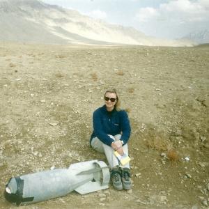 War Reporter Alex Quade in Afghanistan 2002. Sitting next to unexploded ordnance.