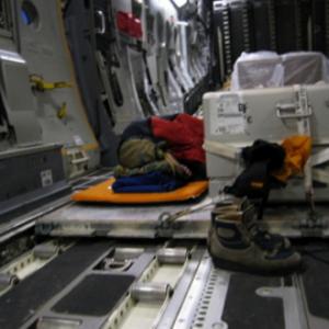 War Reporter Alex Quade sleeping next to caskets onboard Air Force cargo plane en route to Afghanistan. 2007.