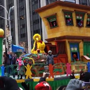 Raina Cheng (Zebra coat w/pink scarf) on the Sesame Street Float waving at crowds at the 88th Macy's Thanksgiving Day Parade, 2014