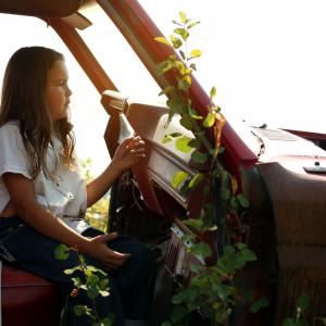 Elias Louie sits in an abandoned car in a 'car cemetery' on the Tl'etinqox reserve while filming 'Clouds of Autumn'.