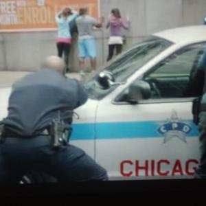 Screenshot was taken from a sneak peak promo of the Chicago PD episode Push the Pain Away Garret is the CPD Police Officer to the left of Jon Seda and Jason Beghe positioned across the driver side fender