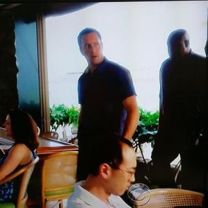 Sitting at a table while Alex OLoughlin and Chi McBride walk behind me On Season 5 episode 21