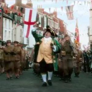 David Hinde As 'Walmington On Sea Town Crier' Leading The St Georges Day Parade In Dads Army Movie 2016 Universal Pictures.Filmed In Bridlington Old Town,East Yorkshire.England UK